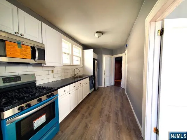 a kitchen with stainless steel appliances granite countertop wooden cabinets a stove top oven a sink and dishwasher with wooden floor