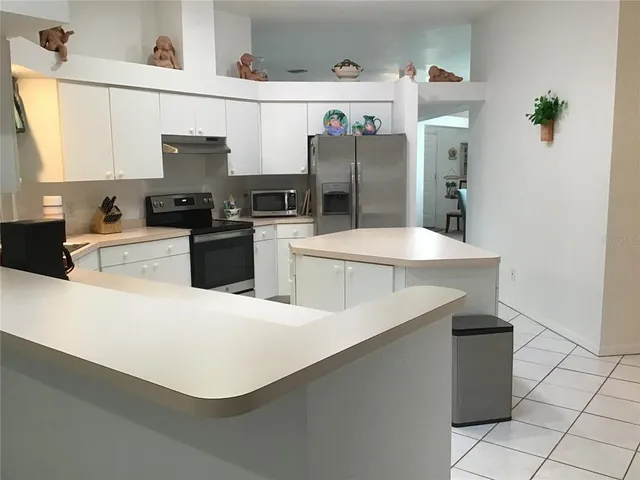a kitchen with stainless steel appliances a refrigerator sink stove and white cabinets
