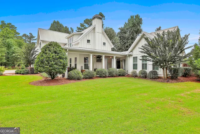 a view of white house with a small yard and large tree