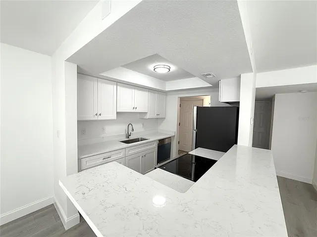 a kitchen with stainless steel appliances a refrigerator sink and white cabinets