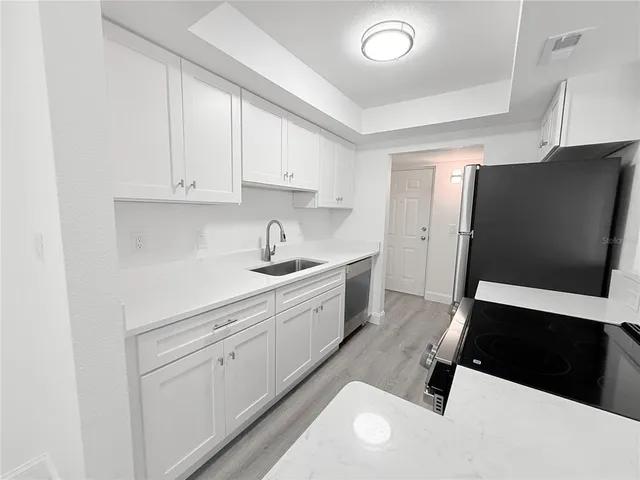 a kitchen with stainless steel appliances white cabinets and a refrigerator