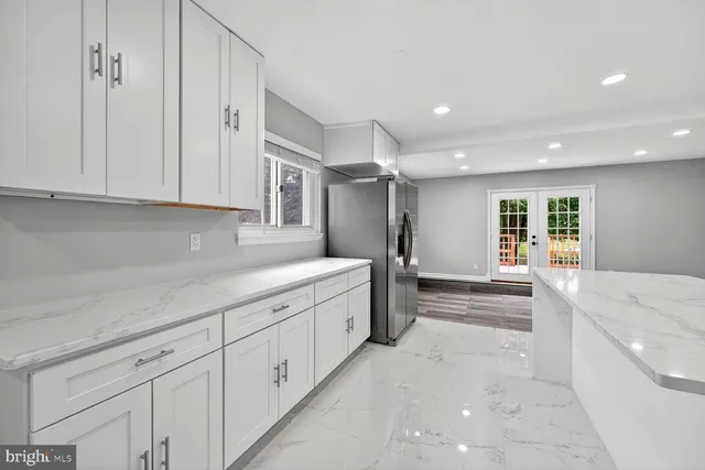 a large kitchen with white cabinets stainless steel appliances and a counter top space