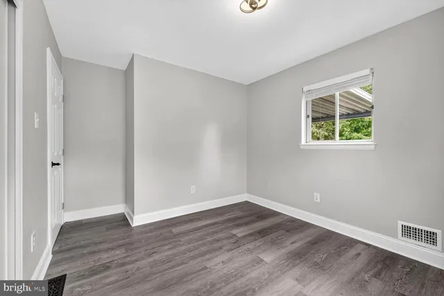 a view of an empty room with wooden floor and a ceiling fan