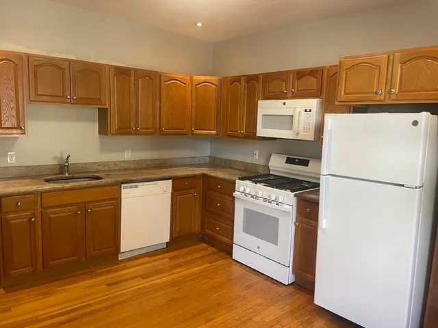 a kitchen with granite countertop a refrigerator stove top oven and sink