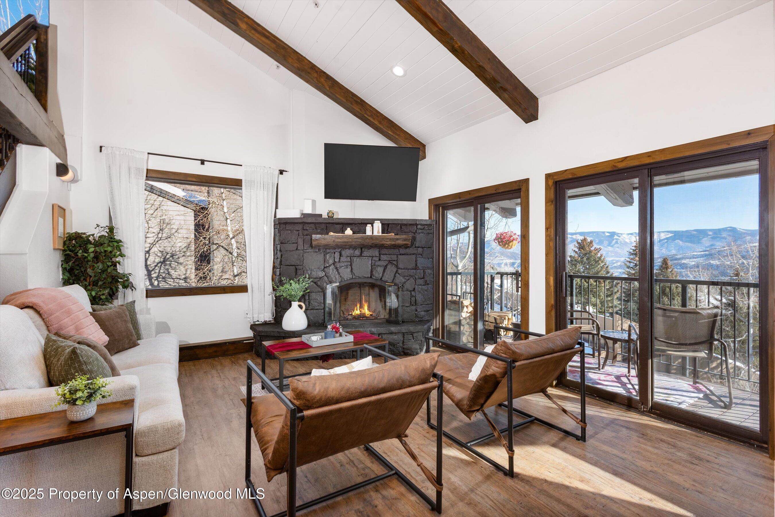 55 Upper Woodbridge Road, Unit J5 Snowmass Village, CO 81615 - Photo 1 of 32 a living room with furniture a flat screen tv and a floor to ceiling window