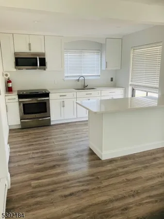 a kitchen with kitchen island granite countertop a stove a sink and a microwave