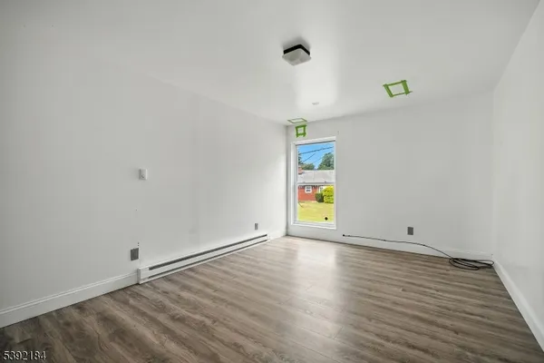 a view of an empty room with wooden floor and a window