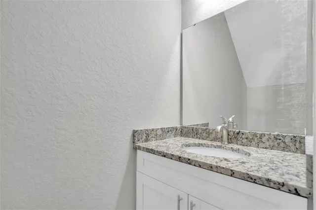 a bathroom with a granite countertop sink and a mirror