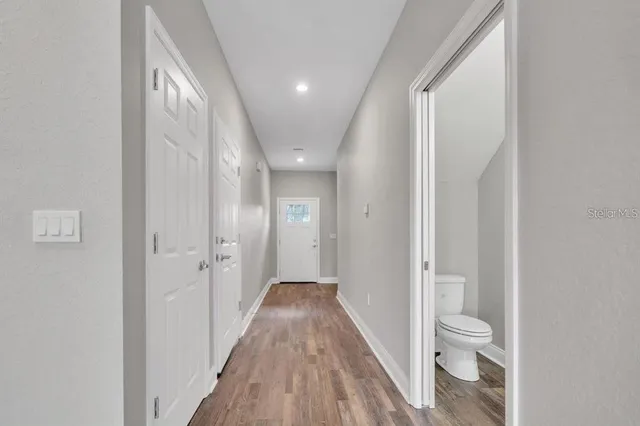 a view of a hallway with wooden floor and a bathroom