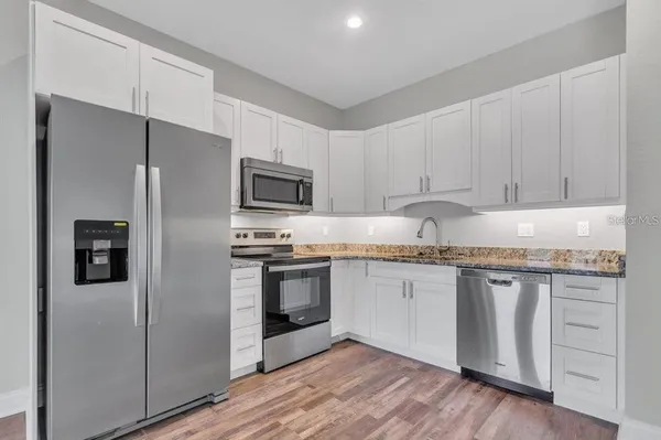 a kitchen with granite countertop white cabinets and stainless steel appliances