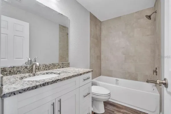 a bathroom with a granite countertop sink a toilet and bathtub
