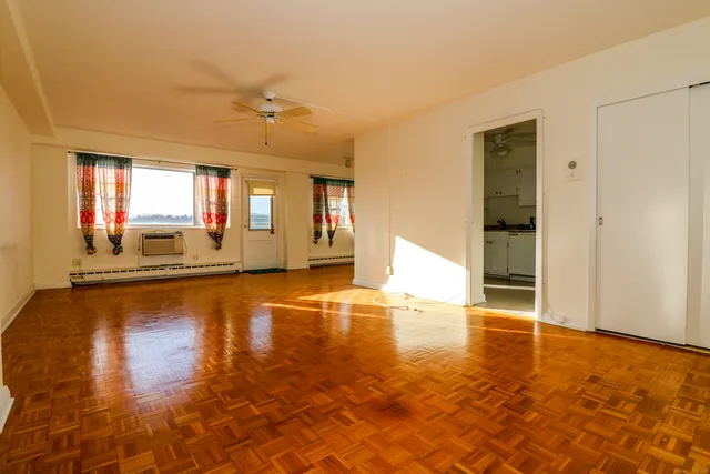a view of empty room with wooden floor and fan