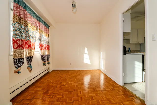 an empty room with a chandelier fan and windows
