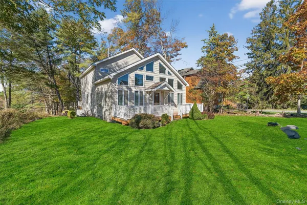 a view of a house with a big yard and large trees