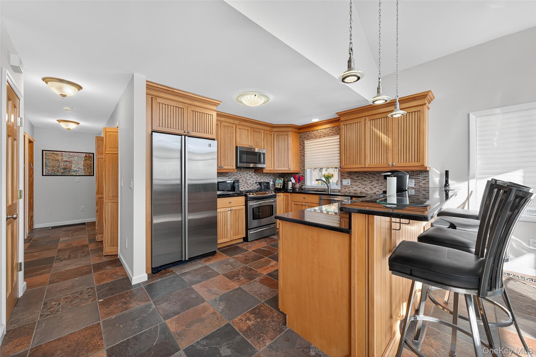 518 Sackett Lake Road Monticello, NY 12701 - Photo 18 of 44 a kitchen with stainless steel appliances granite countertop a refrigerator a stove a sink a dining table and chairs with wooden floor