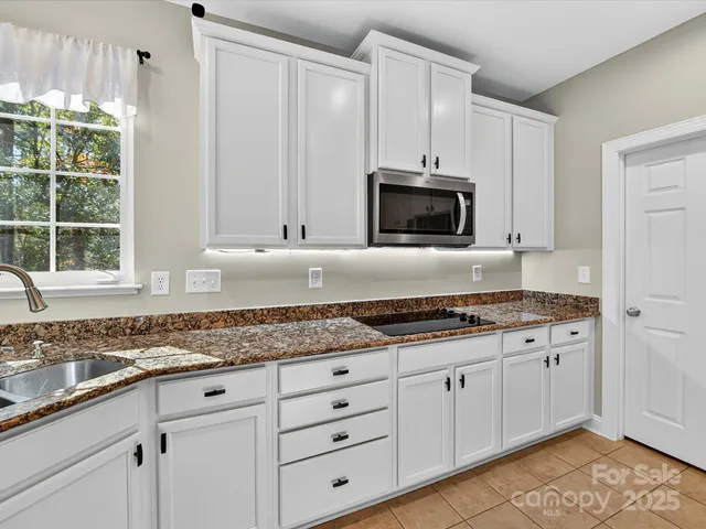 a kitchen with granite countertop white cabinets and stainless steel appliances