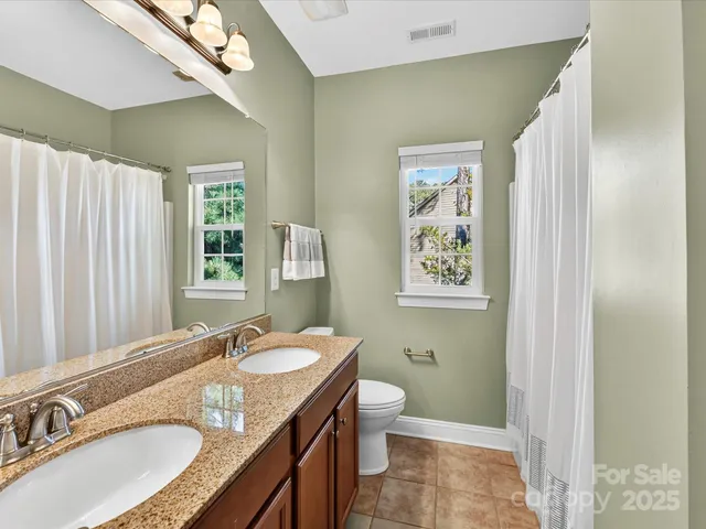 a bathroom with a granite countertop sink a mirror a toilet and a shower