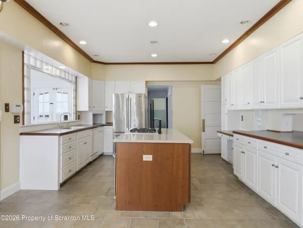 a large white kitchen with kitchen island a sink a stove and a refrigerator