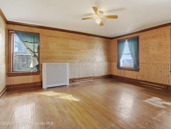 an empty room with wooden floor and a ceiling fan