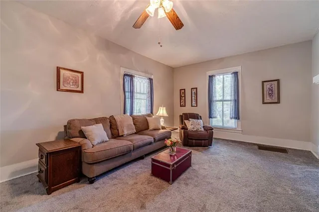 a living room with furniture a ceiling fan and a flat screen tv