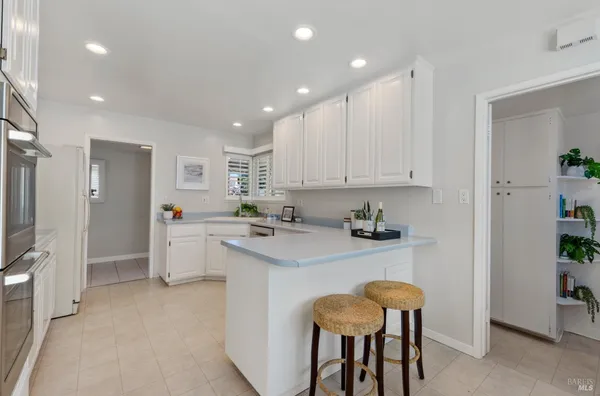 a kitchen with stainless steel appliances granite countertop a white table chairs and a refrigerator