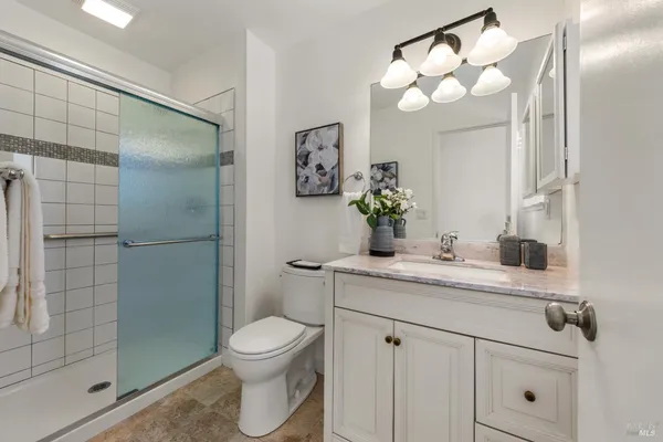 a bathroom with a granite countertop sink a toilet and shower