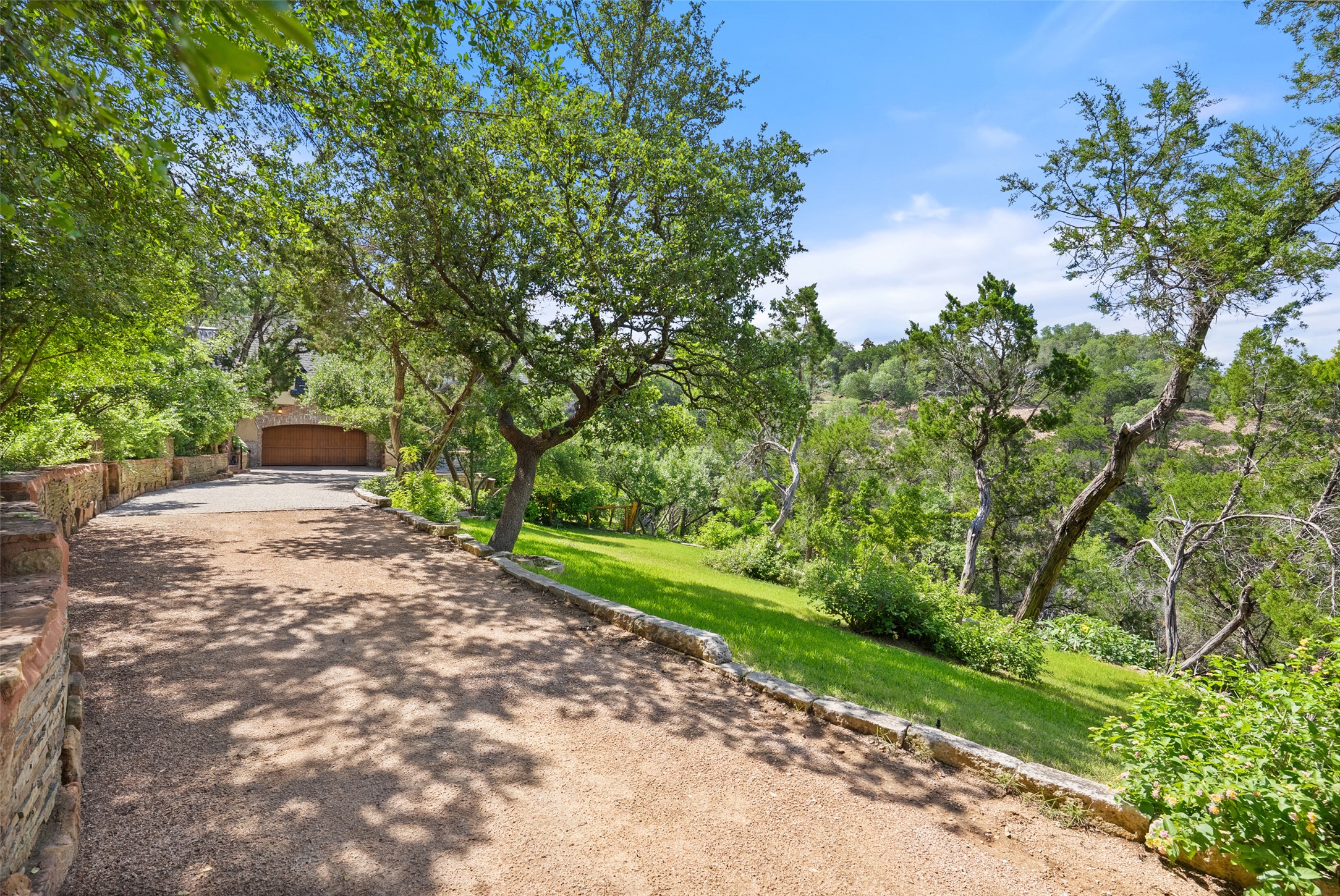 1354 The High Road Austin, TX 78746 - Photo 33 of 40 The rear private driveway winds through lush greenery, leading to a secluded garage entrance.