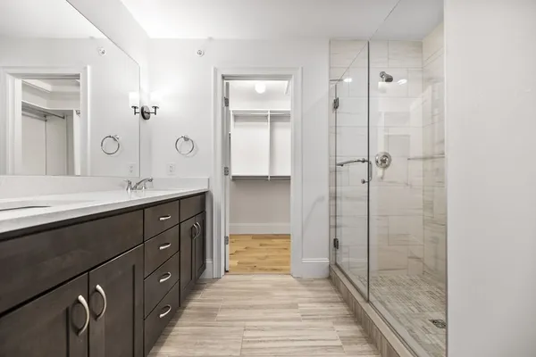 a bathroom with a double vanity sink a mirror and a shower