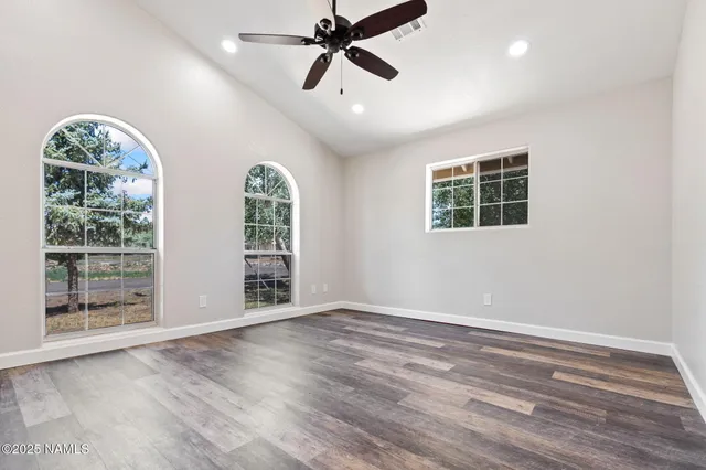 a view of an empty room with a window and wooden floor