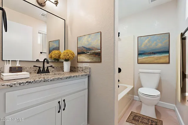 a bathroom with a granite countertop sink mirror vanity and toilet