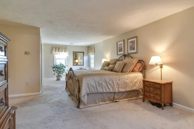 a spacious bedroom with a bed a lamp and window