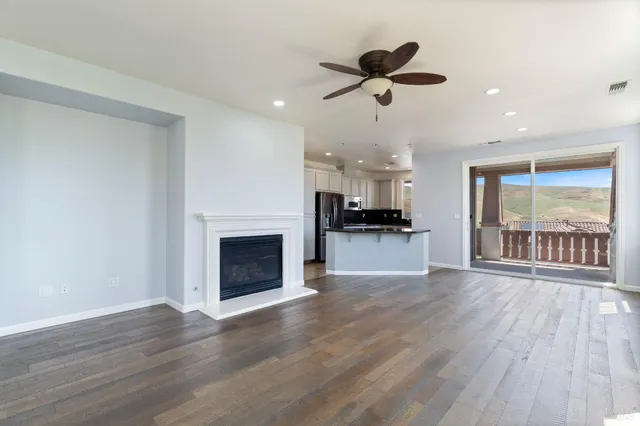 an empty room with wooden floor fireplace and windows