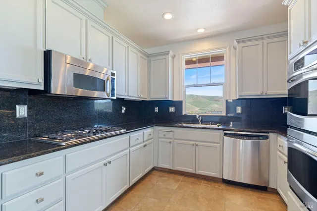 a kitchen with granite countertop a sink stainless steel appliances and cabinets