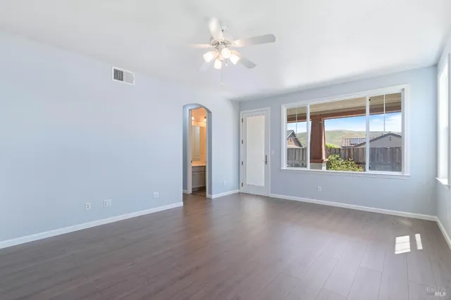 a view of an empty room with a window and wooden floor