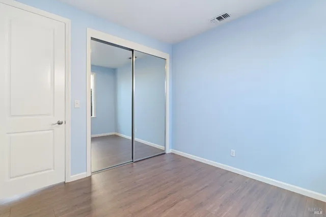 an empty room with wooden floor and closet