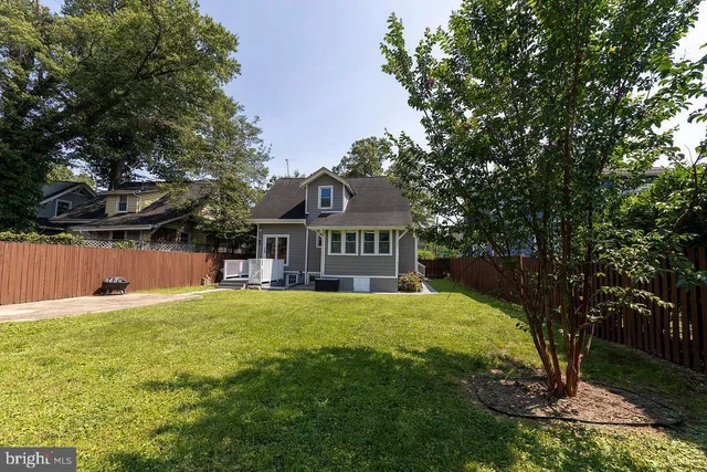a front view of a house with a yard and large trees