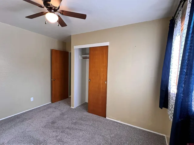 an empty room with closet and a chandelier fan
