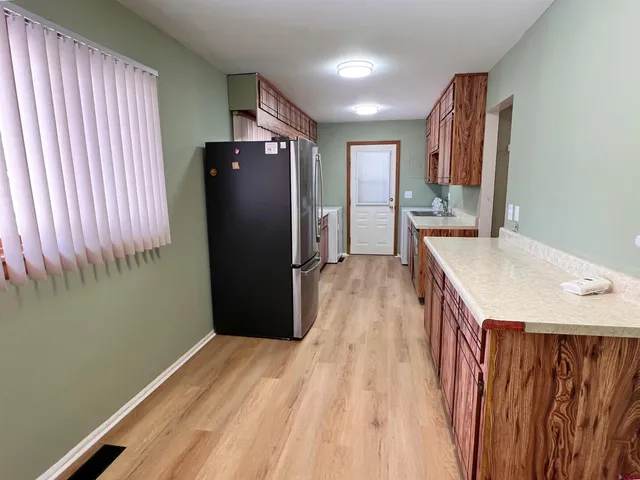 a kitchen with stainless steel appliances granite countertop a refrigerator a stove and a sink with wooden floor