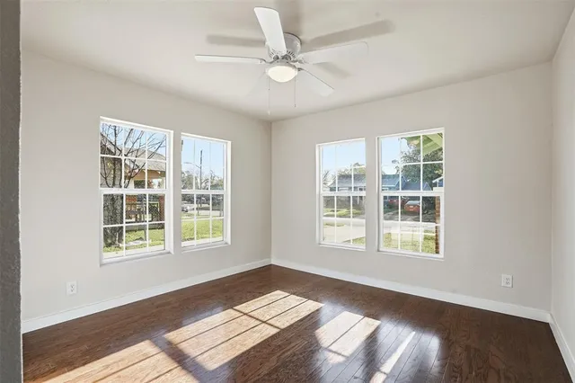 an empty room with wooden floor and ceiling fan