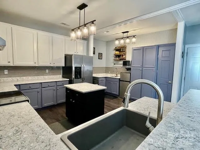 a kitchen with a refrigerator a stove a sink and white cabinets