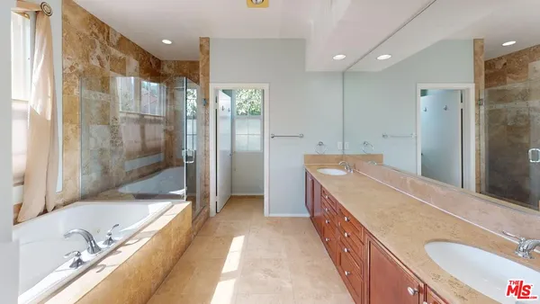a bathroom with a granite countertop double vanity sink and a bathtub