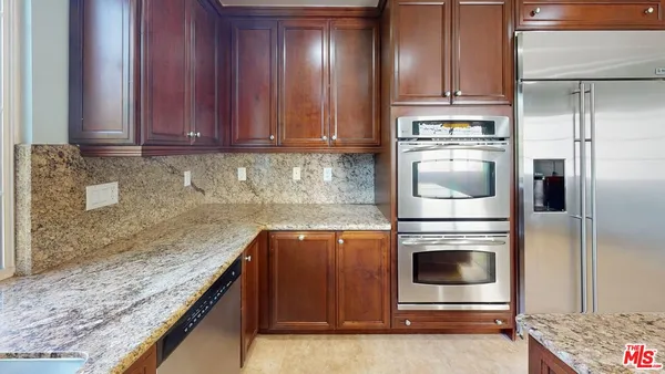 a kitchen with granite countertop wooden cabinets and a stove top oven