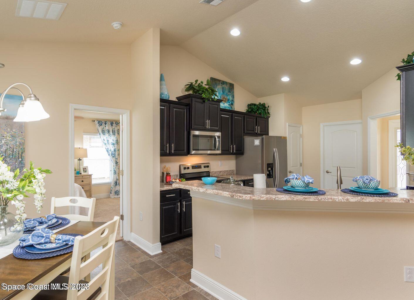 362 Garvey Road Palm Bay, FL 32908 - Photo 7 of 16 a kitchen with stainless steel appliances kitchen island granite countertop a refrigerator and a stove top oven