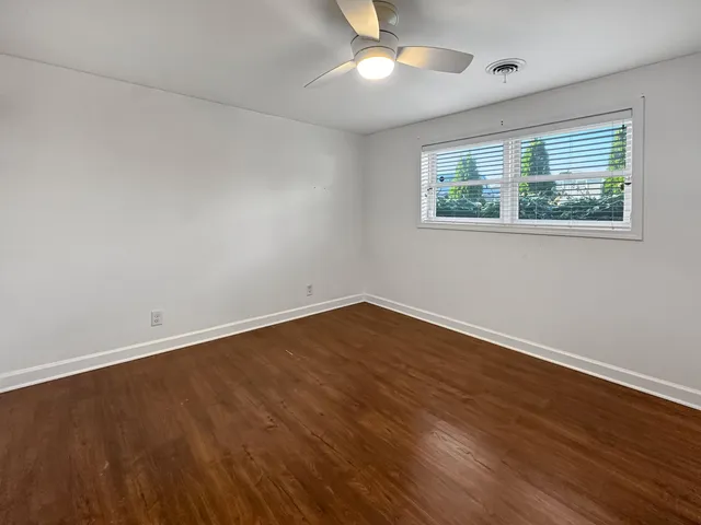an empty room with wooden floor closet and windows