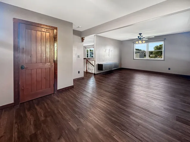 an empty room with wooden floor ceiling fan and windows