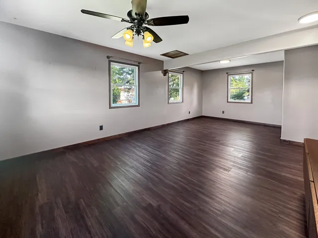 an empty room with windows and ceiling fan