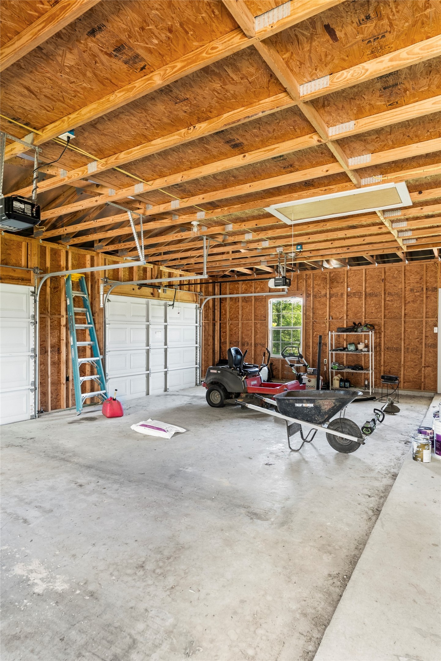 928 Upper Elgin River Road Elgin, TX 78621 - Photo 32 of 40 Spacious two-car garage featuring a concrete floor, exposed wood beam ceiling, and two overhead garage doors.