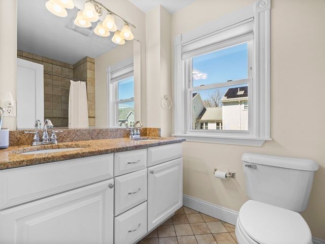 a bathroom with a granite countertop toilet sink and mirror