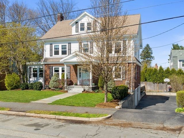a front view of a building with garden and trees