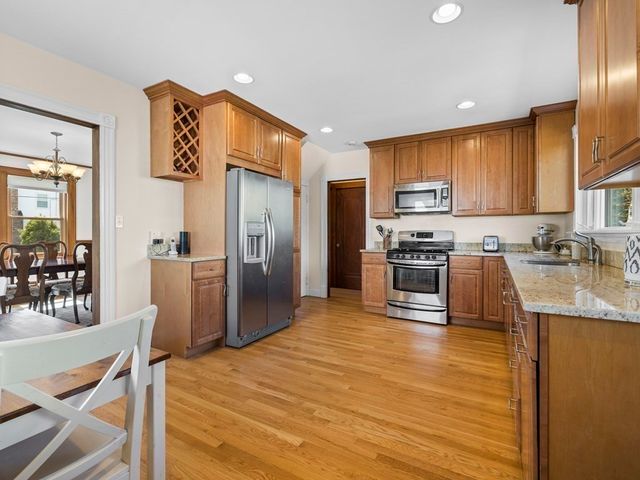 a kitchen with stainless steel appliances granite countertop a refrigerator a stove top oven a sink dishwasher and white cabinets with wooden floor
